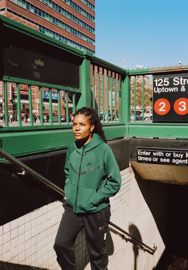 Chiene Joy Jones walking up subway stairs wearing green Nike sweatshirt