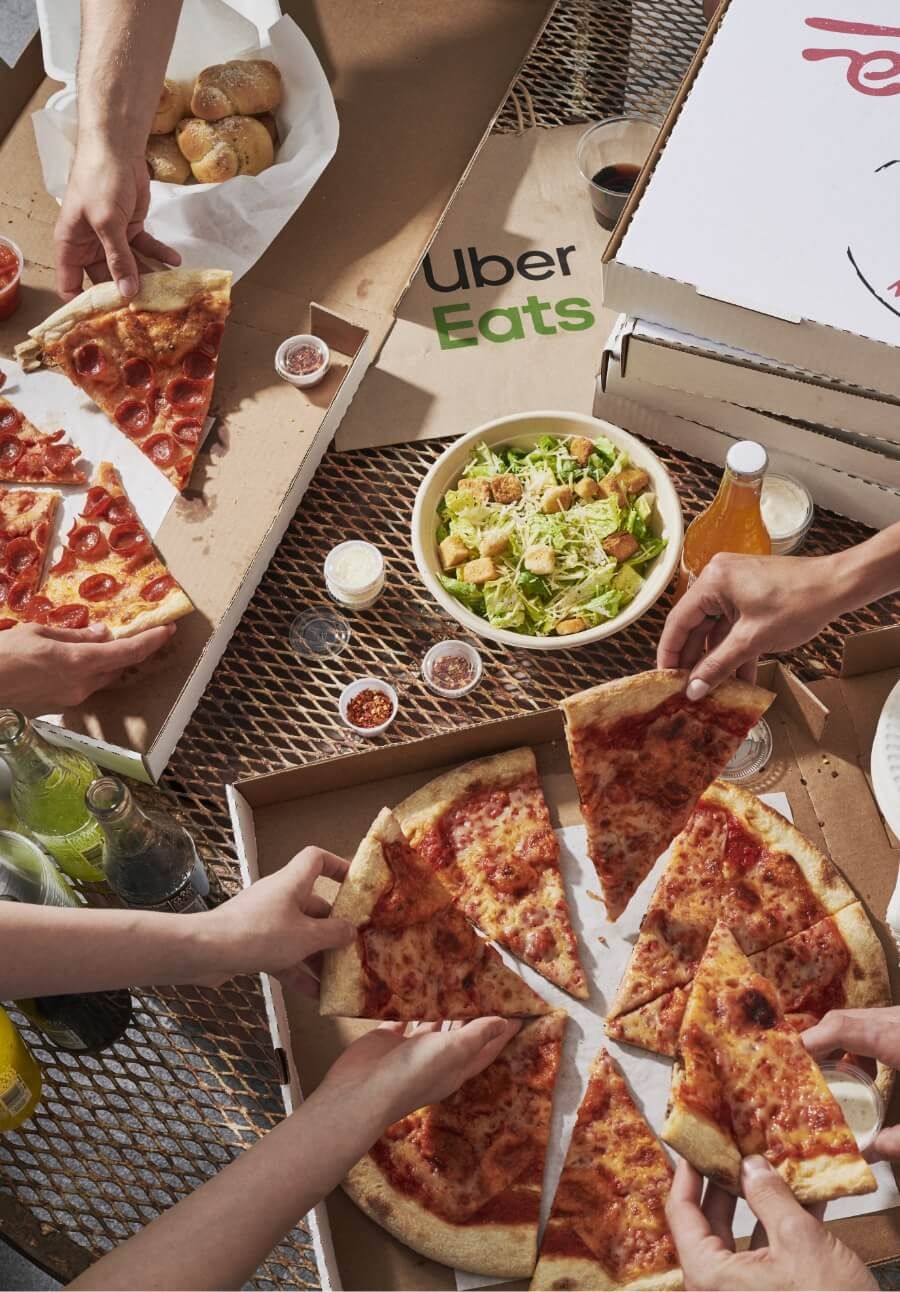 Spread of pizza and salad with uber eats bags