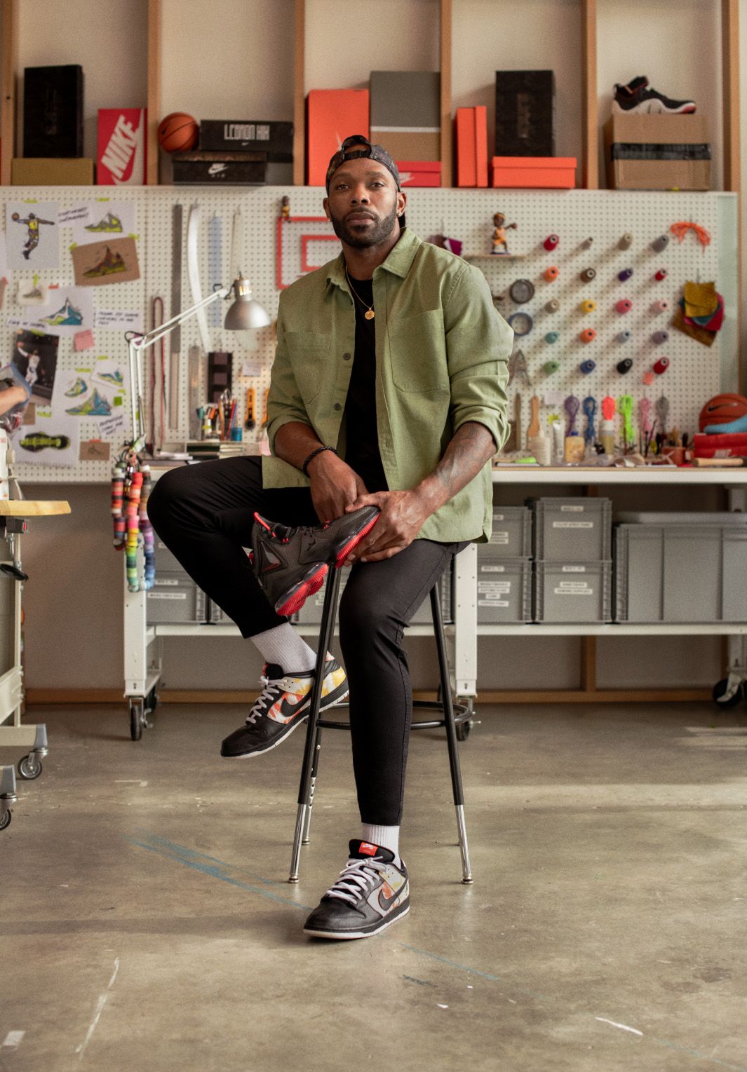 Tim Day sitting on stool with Lebron XIX in front of work bench.