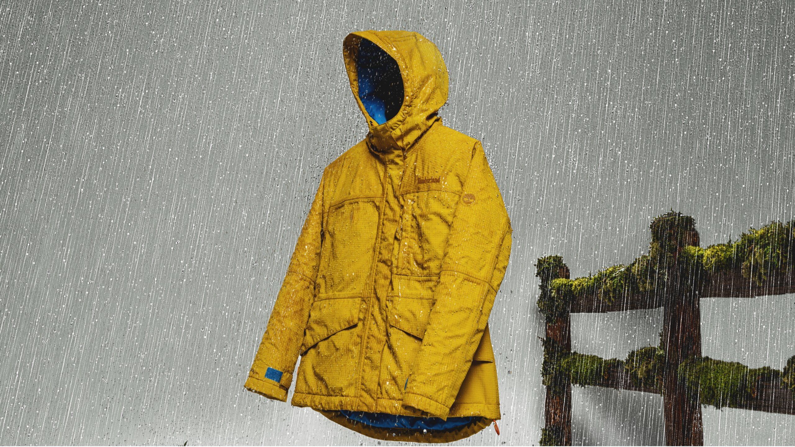Timberland jacket hovering in air next to mossy fence in the rain