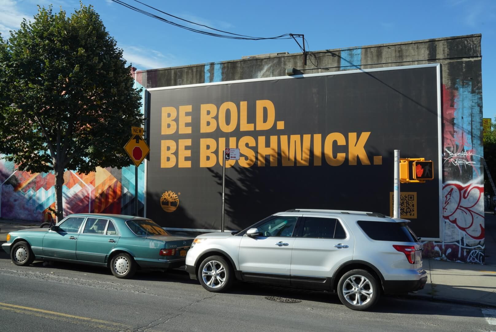 Timberland Be Bold. Be Bushwick. Billboard on street with two cars parked in front