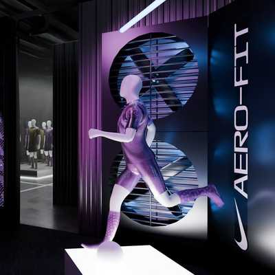 A display with a running mannequin in a sports outfit is shown near a large screen and a vertical "AERO-FIT" sign in a modern, dimly lit showroom.