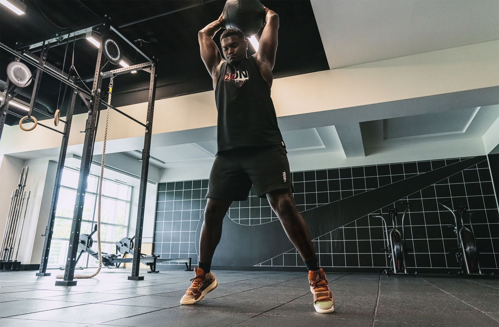 Zion working out in gym with medicine ball over his head