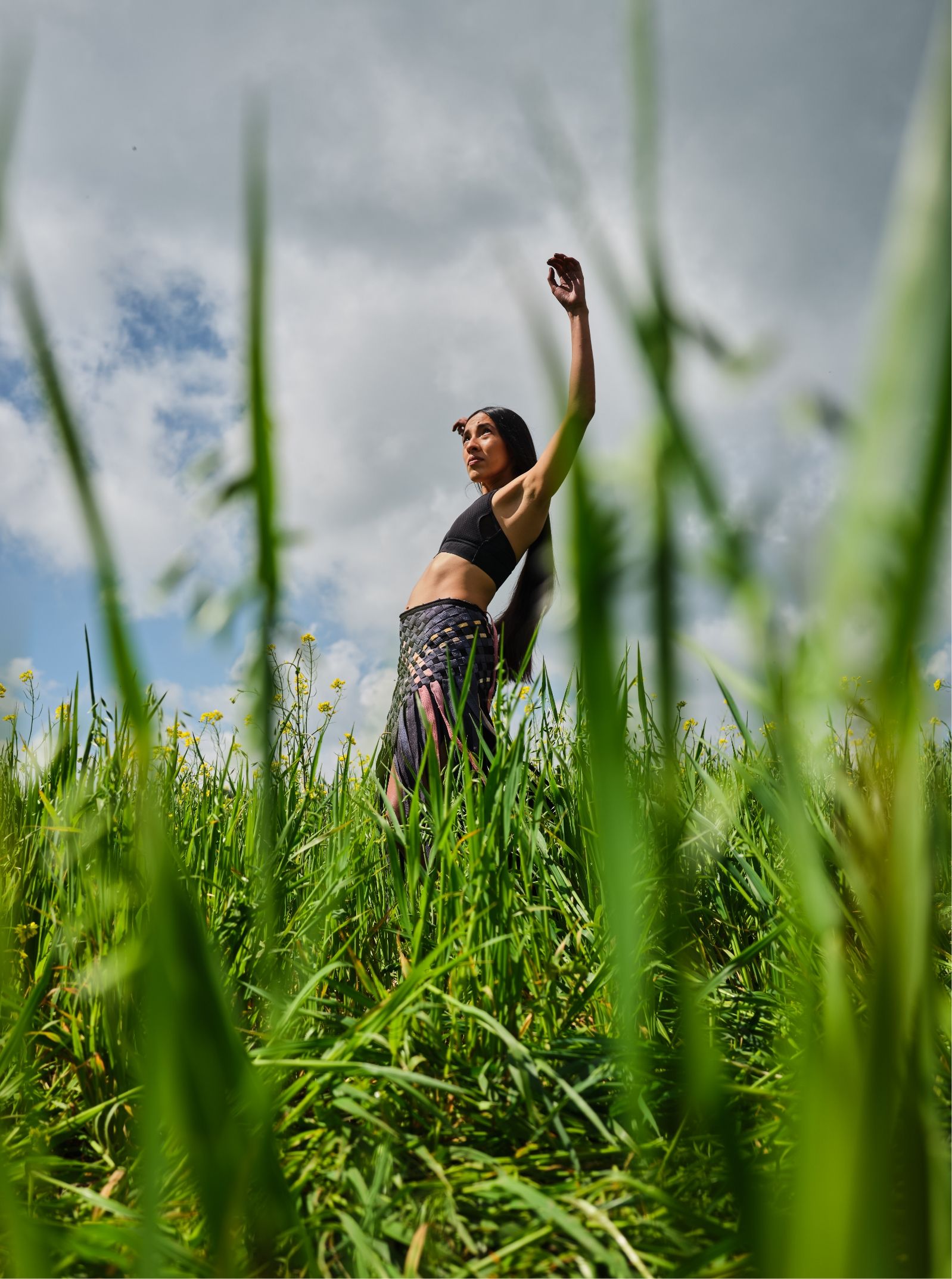 Woman in grassy field with arms raised