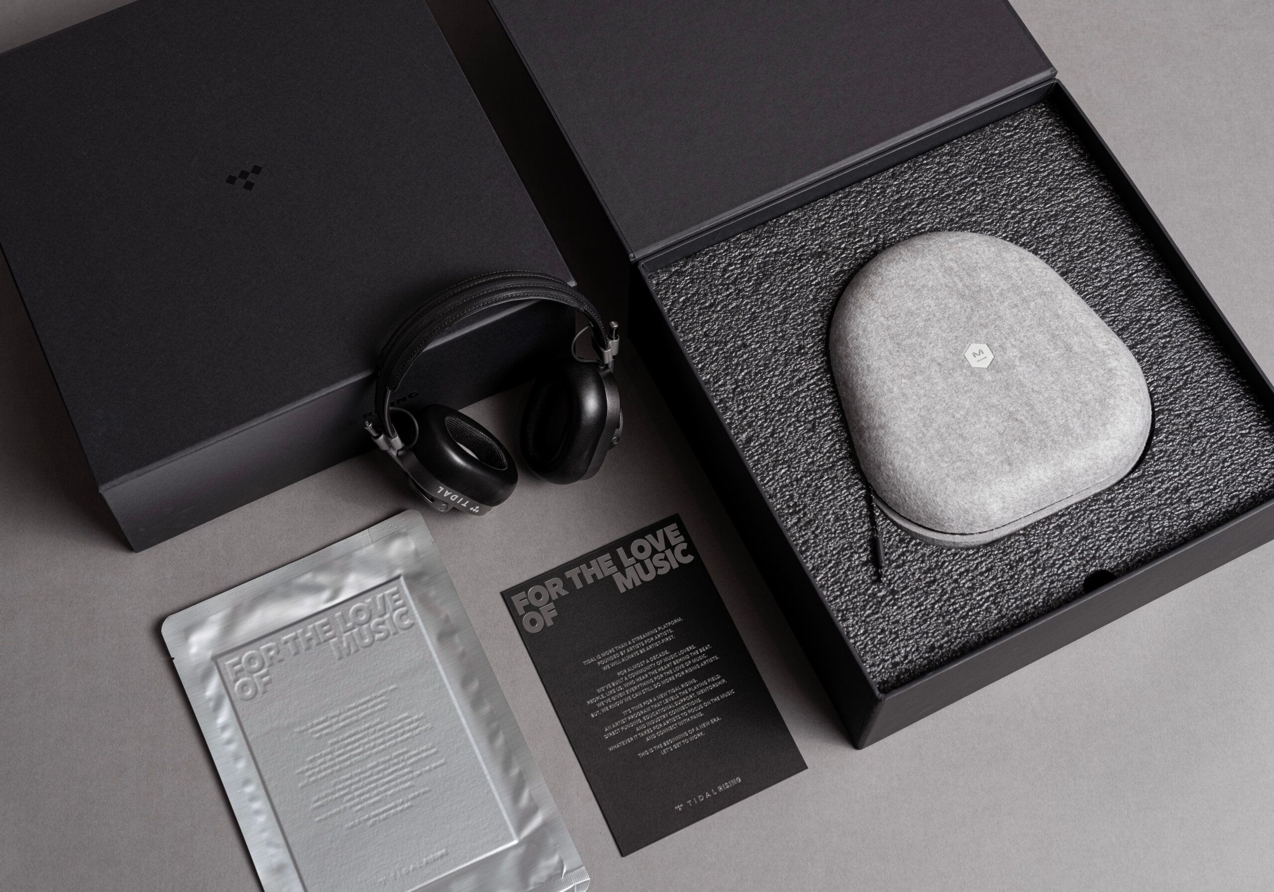 Black promo box for tidal showing headphones and bluetooth speaker along with vaccuum sealed letterpress For the love of music letter.