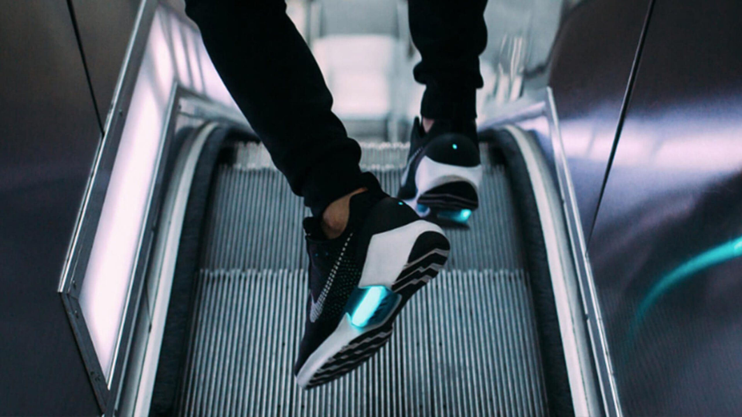 close up of feet wearing Nike Hyper Adapt sneakers starting to walk down escalator