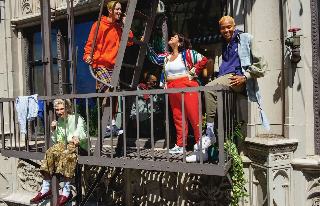 Group of people in bright, colorful clothing hanging out on fire escape of building