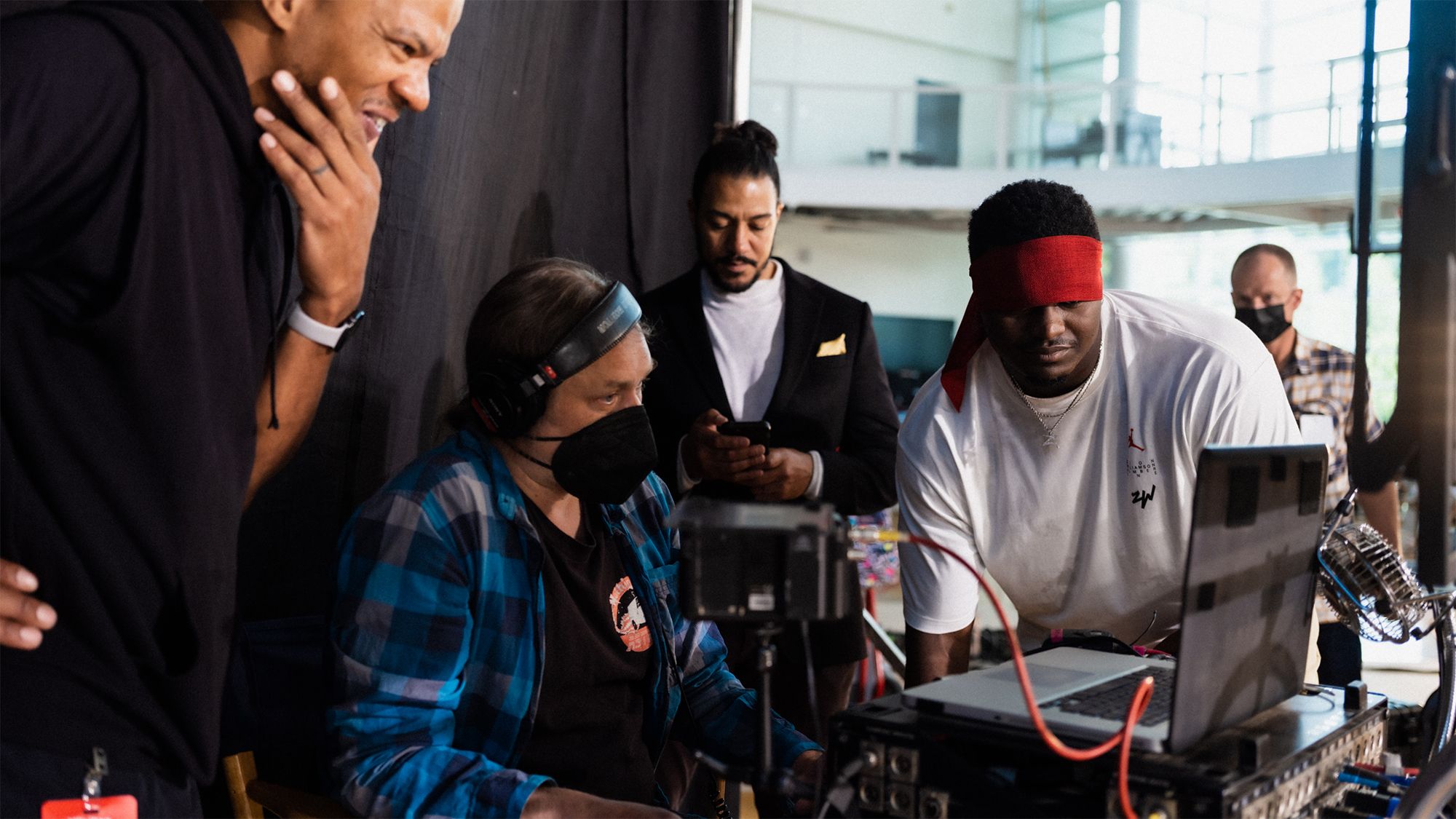 Zion and crew looking at footage after a take. Zion has blindfold pulled up onto his head