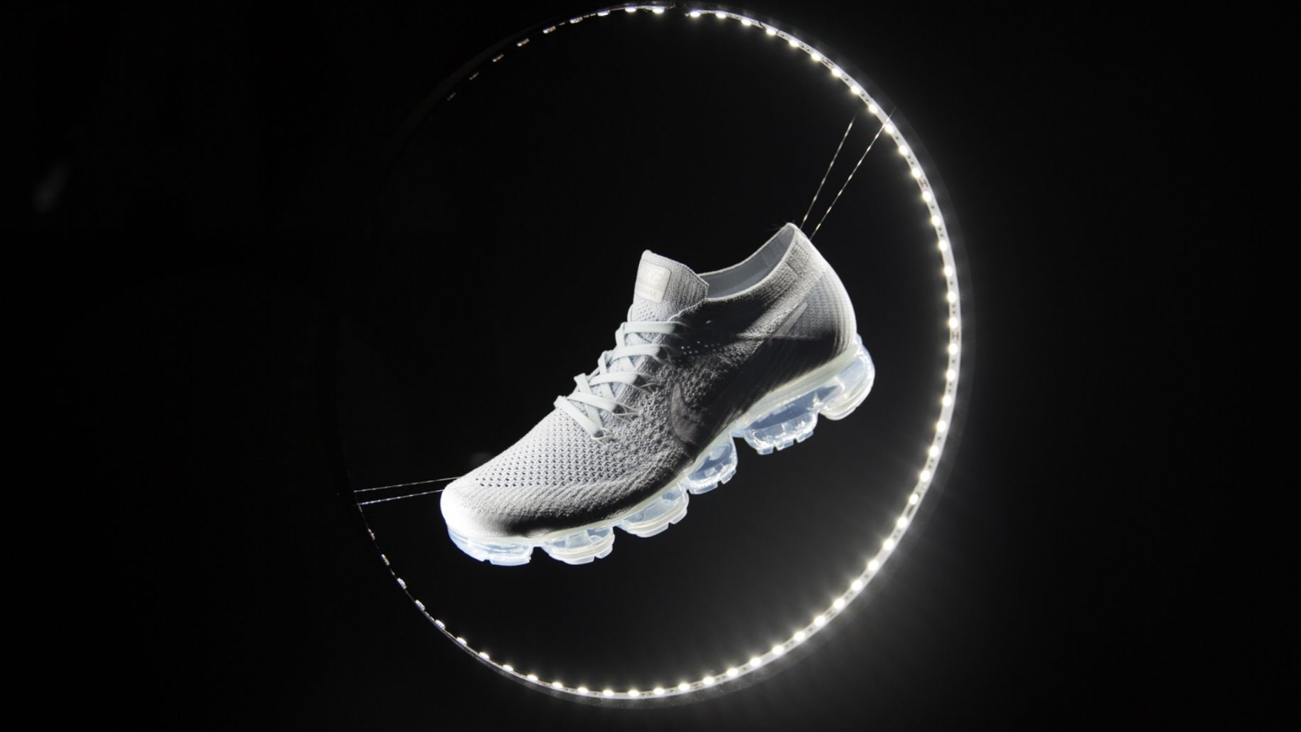Nike air vapor max against black background. a crescent of dots of light surround right side of shoe
