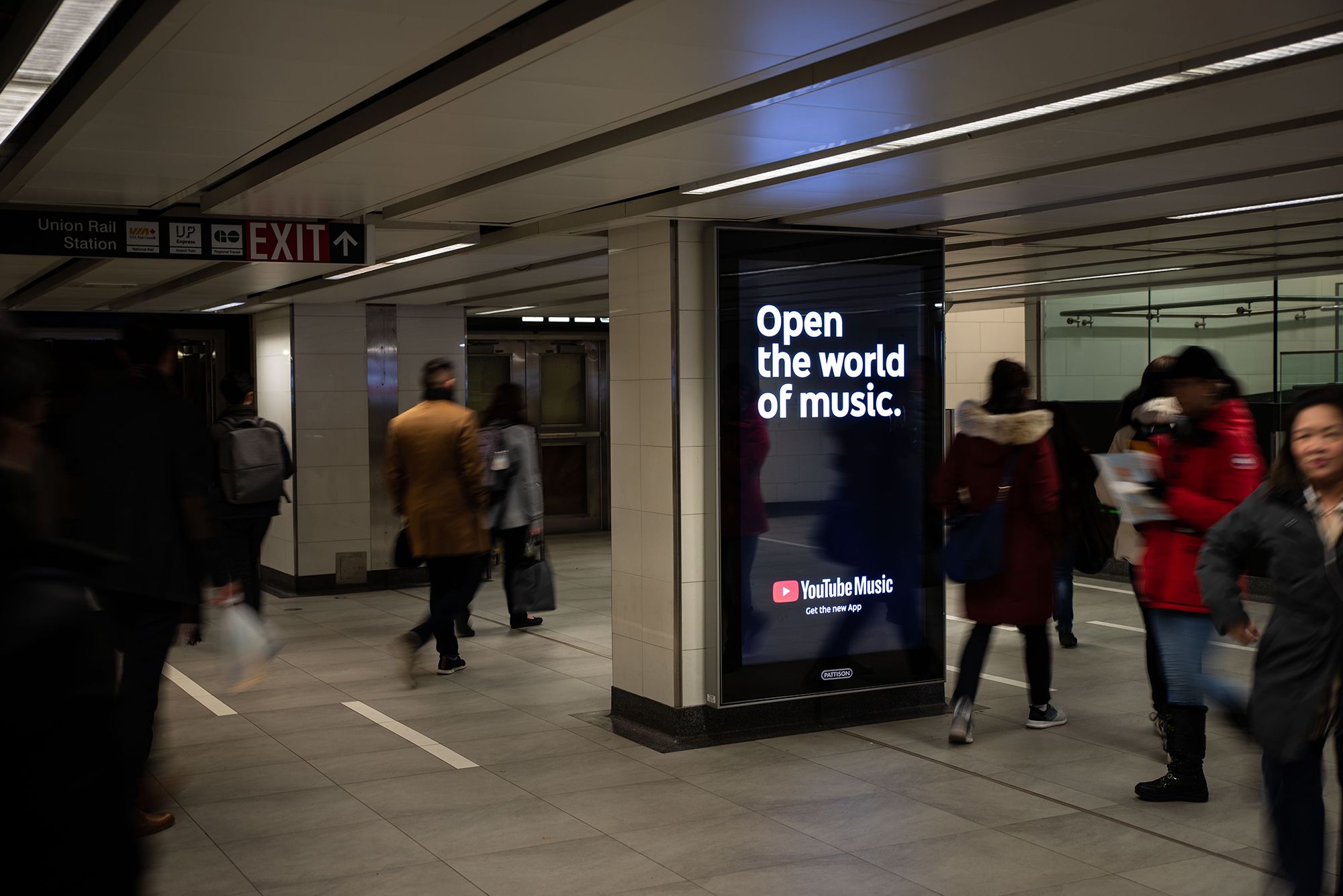 Digital Sign in train station says Open the world of music. Youtube Music Get the new app