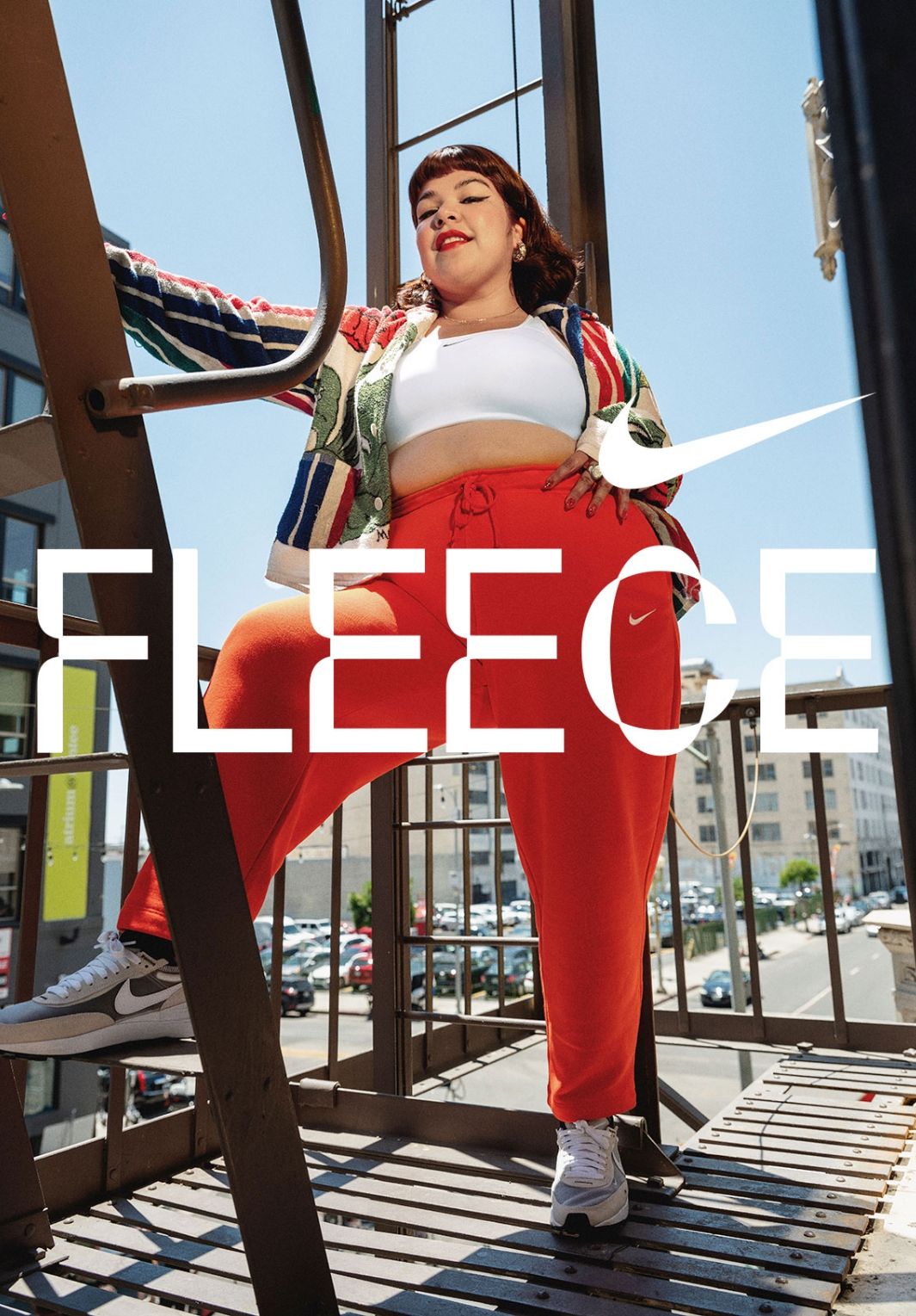 Women in bright red pant posing on fire escape on sunny day. Nike Fleece Logo