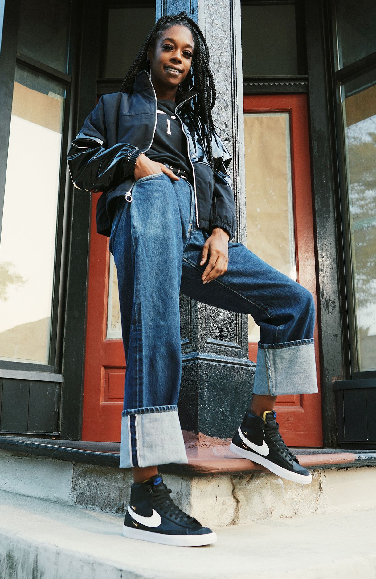 Tamara in street clothes on door step wearing black Nike high tops