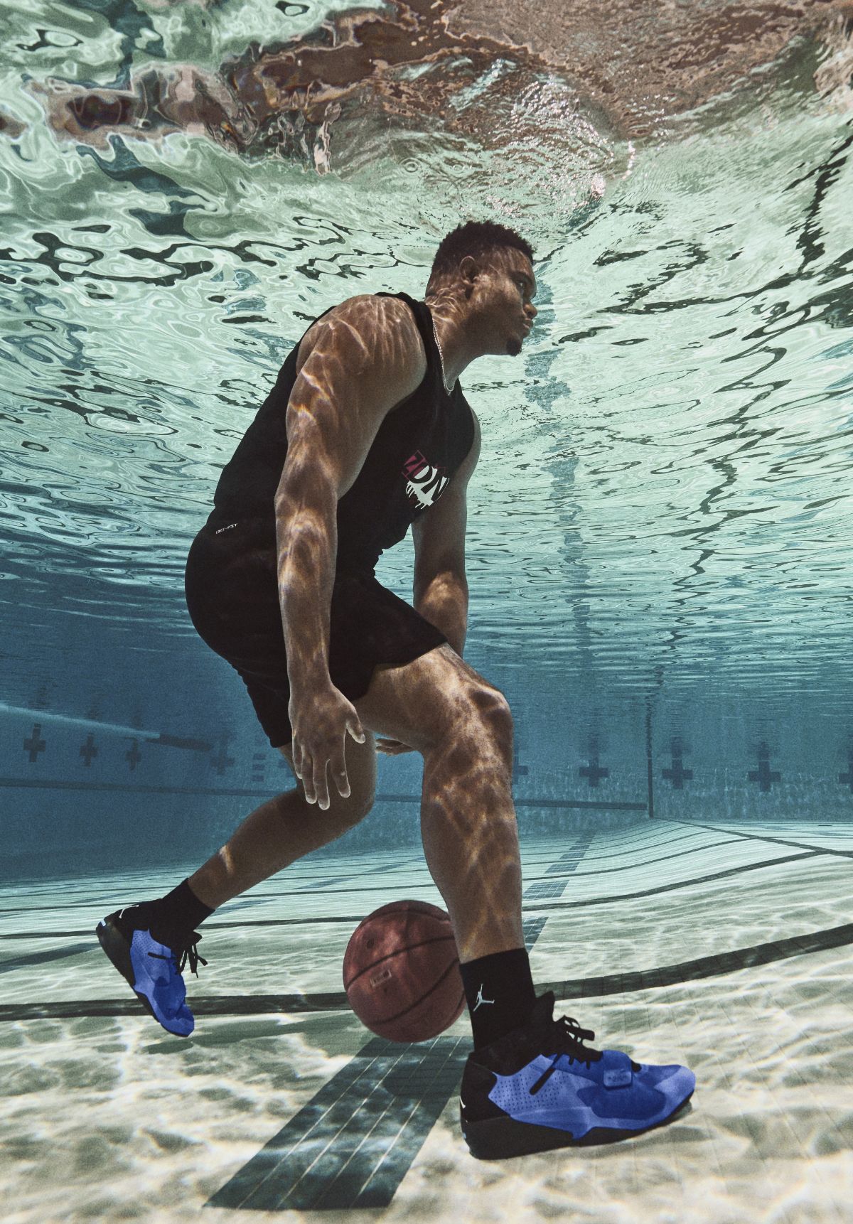 Zion dribbling basketball on bottom of swimming pool wearing blue Nike Zion 2 sneakers
